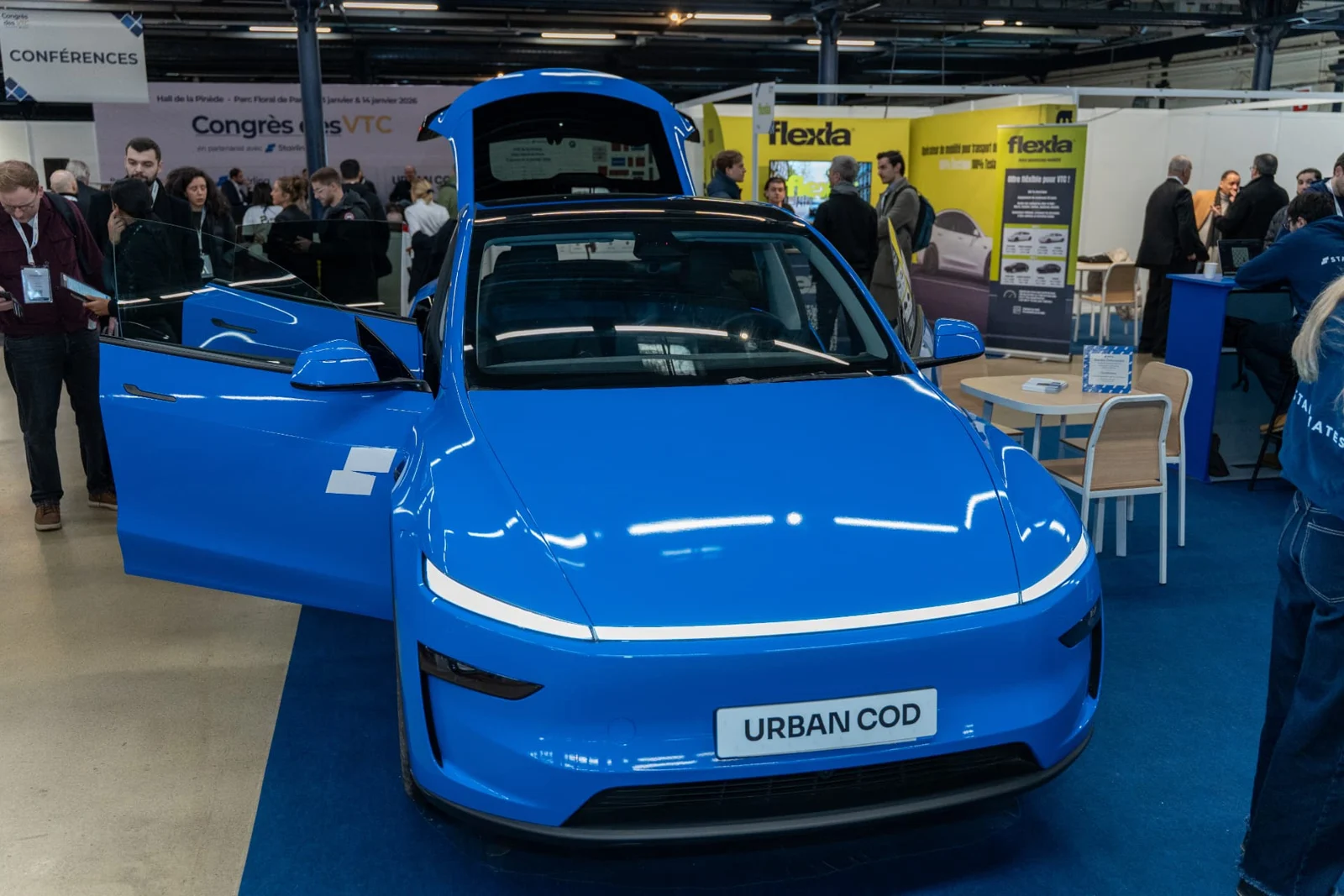 Véhicule électrique bleu présenté sur le salon, à côté du dispositif d’essais véhicules